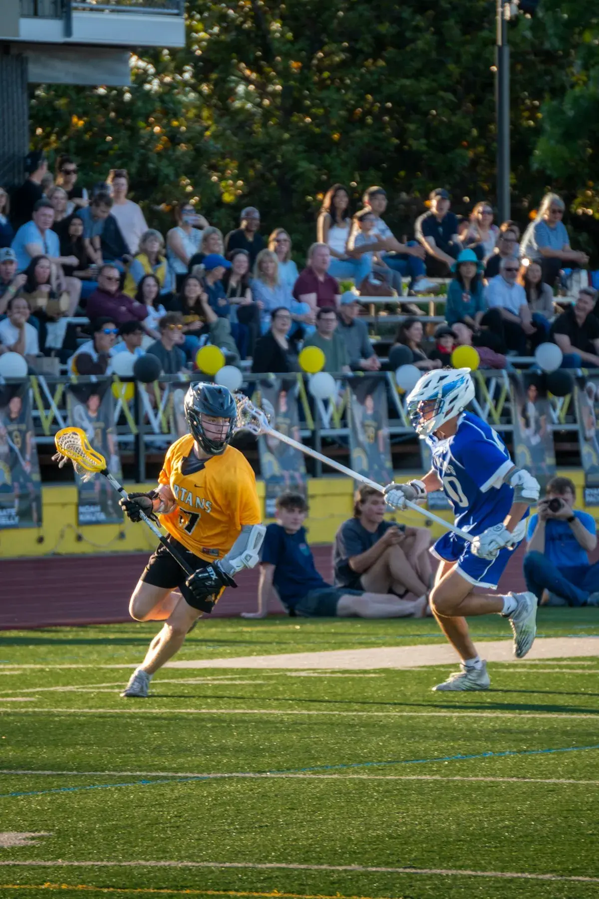 Lacrosse players competing on turf field in spring weather