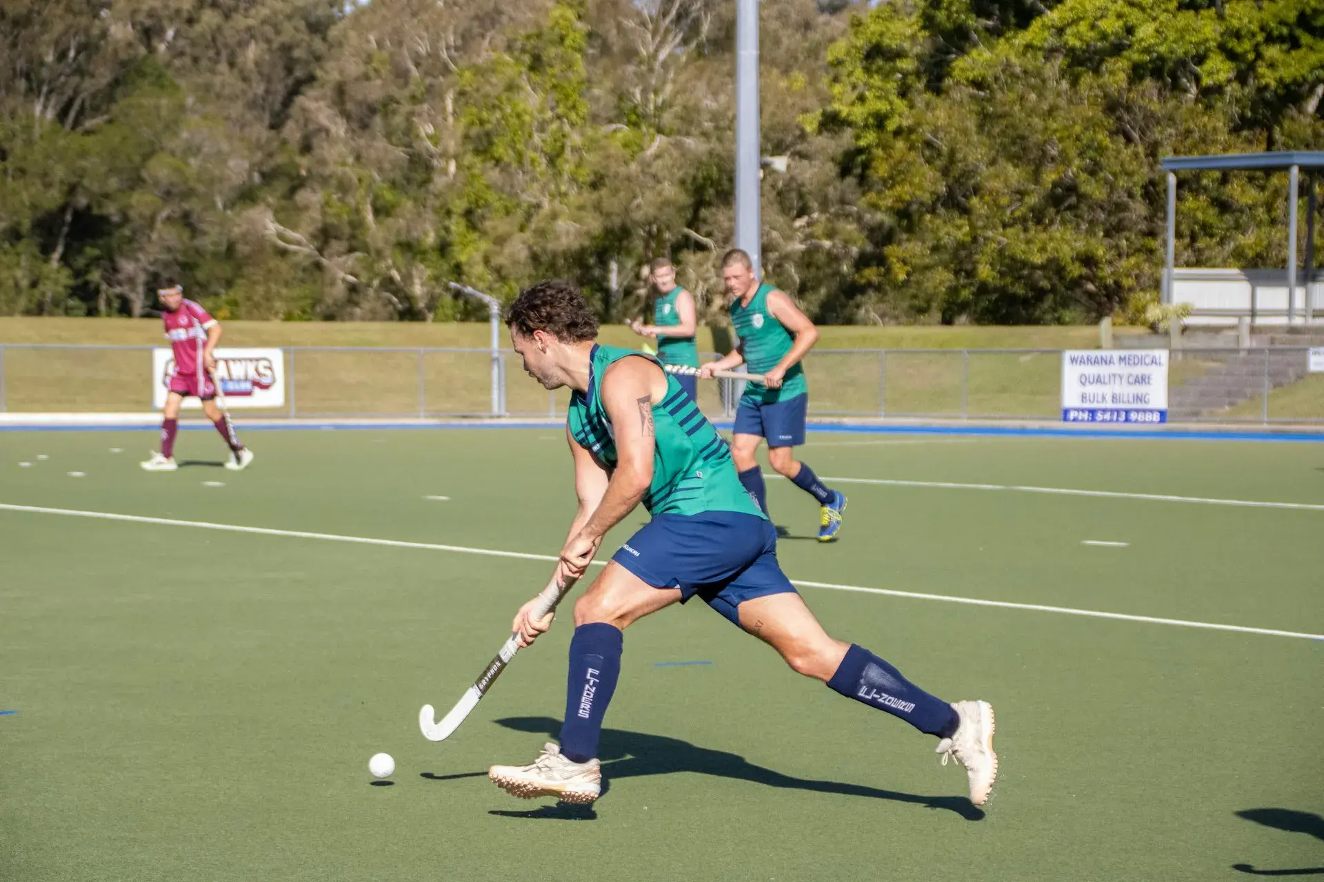 Field hockey players competing on green turf field